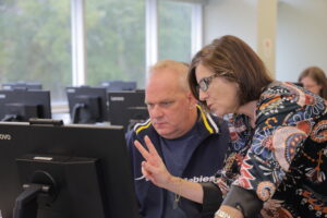 Trainer assisting trainee while both looking at computer